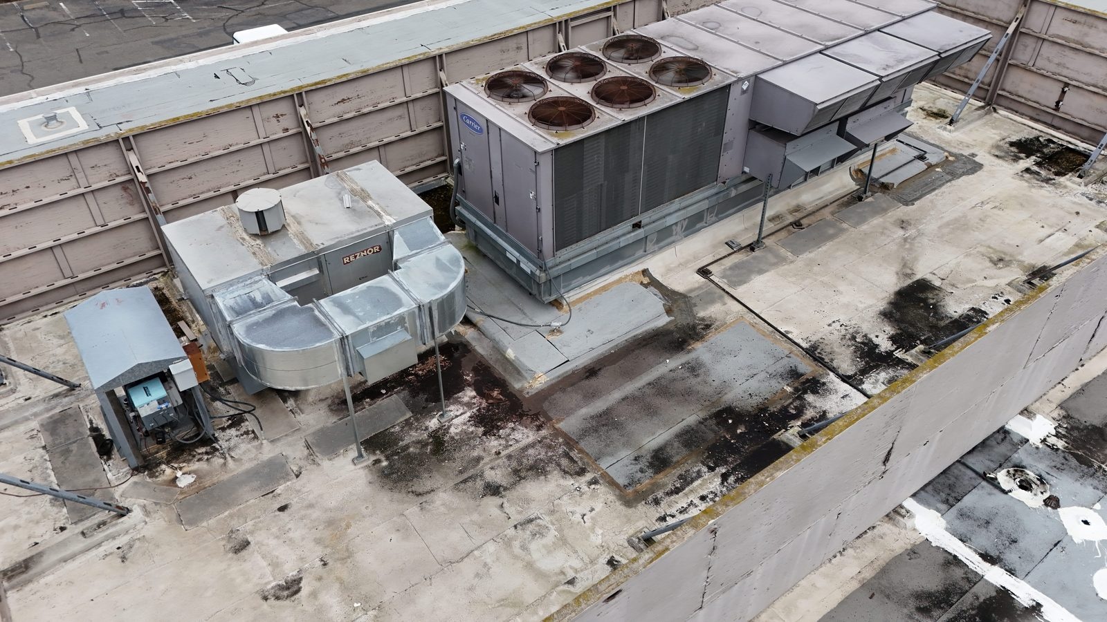Aging rooftop package HVAC unit with visible rust and staining on the surrounding roof surface