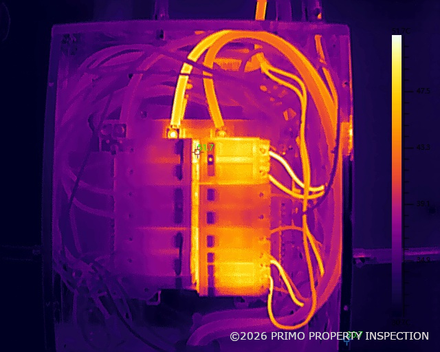 Infrared thermal image of an open electrical panel showing bright yellow-white hot spots at breaker connections and conductors against cooler purple surrounding equipment